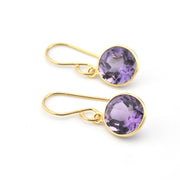 Gold earrings with purple gemstones on a white background