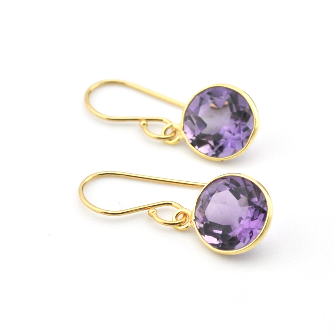 Gold earrings with purple gemstones on a white background