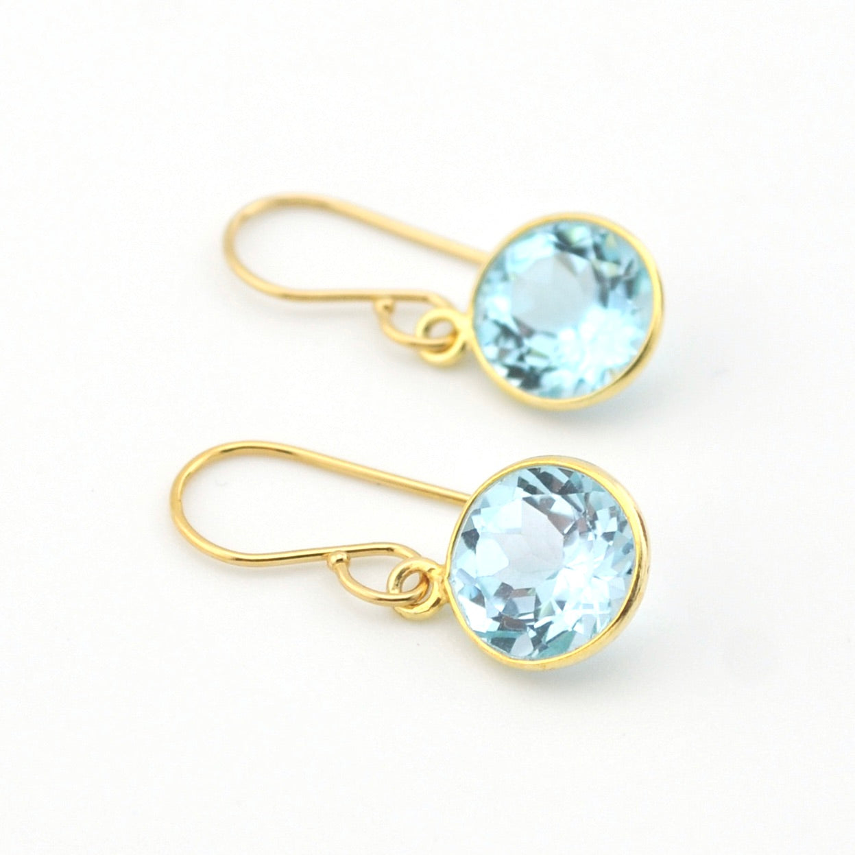 Gold earrings with blue gemstones on a white background