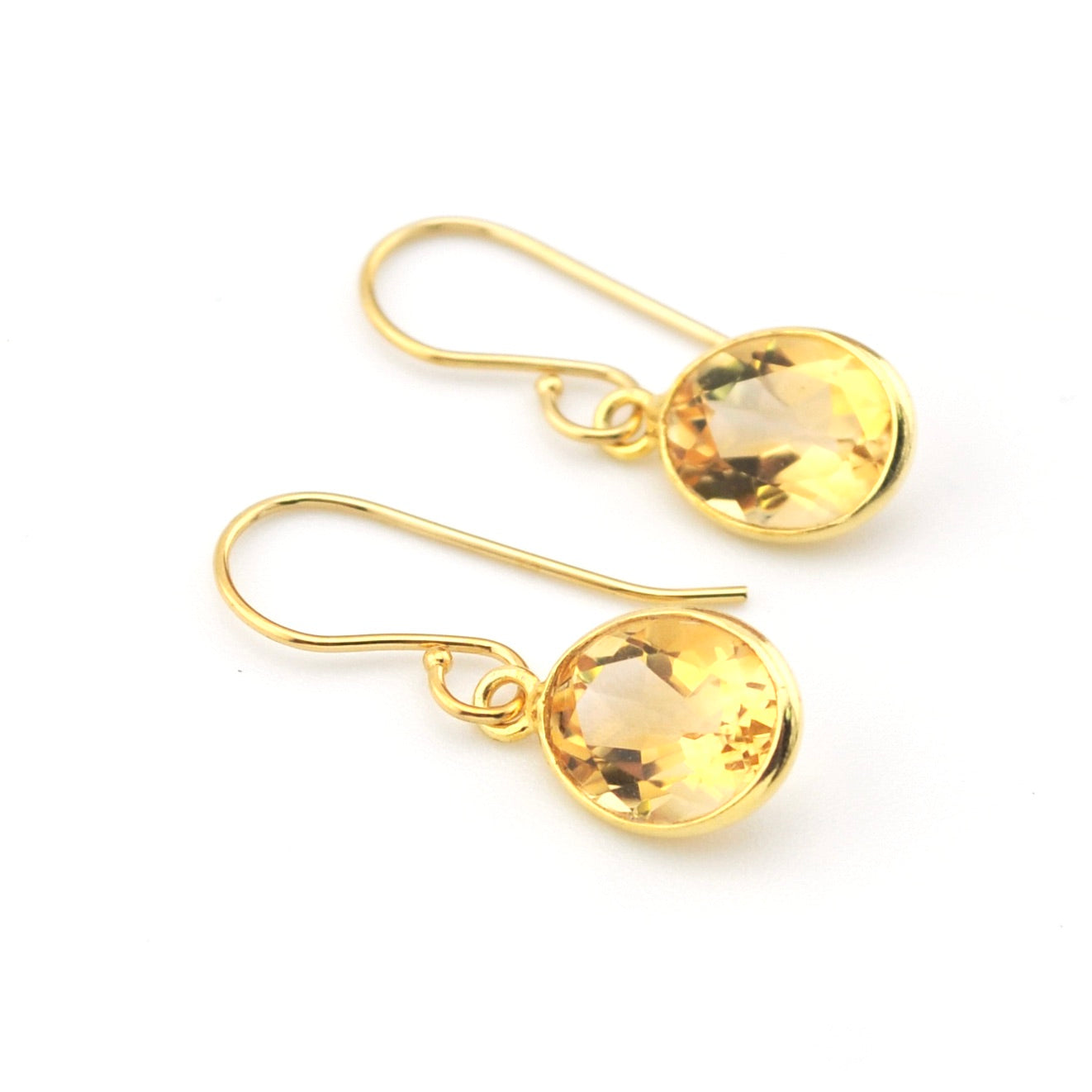 Gold earrings with yellow gemstones on a white background