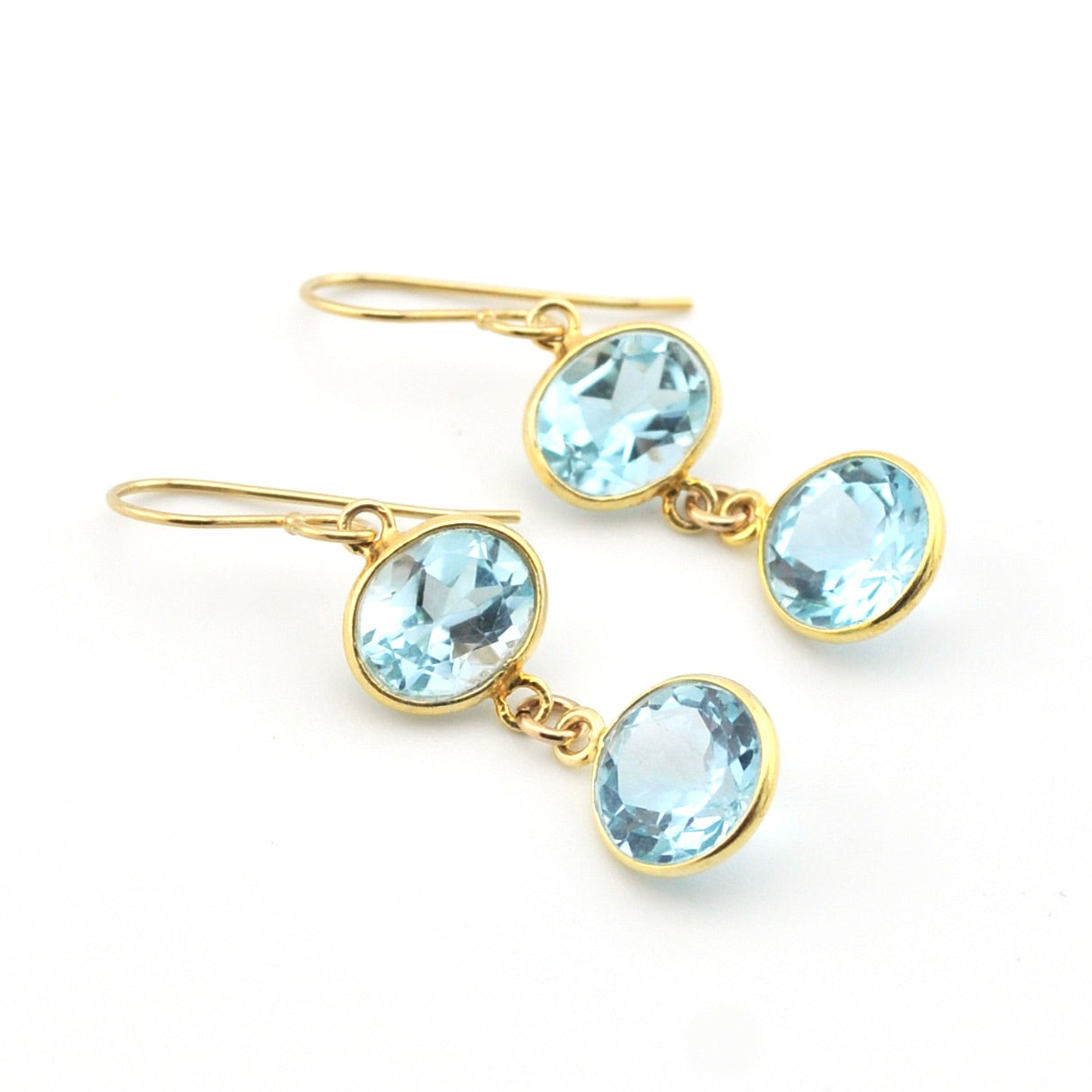 Gold earrings with light blue gemstones on a white background