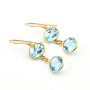 Gold earrings with light blue gemstones on a white background