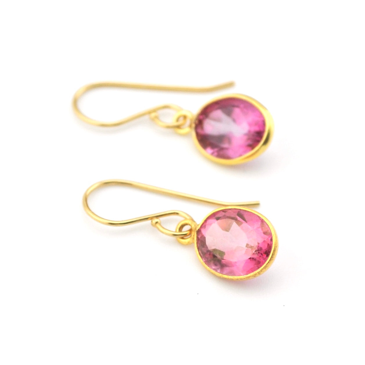 Gold earrings with pink gemstones on a white background