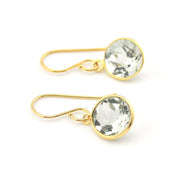 Gold earrings with clear gemstones on a white background