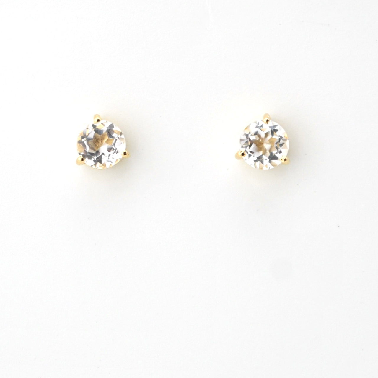 Pair of gold stud earrings with clear gemstones on a white background