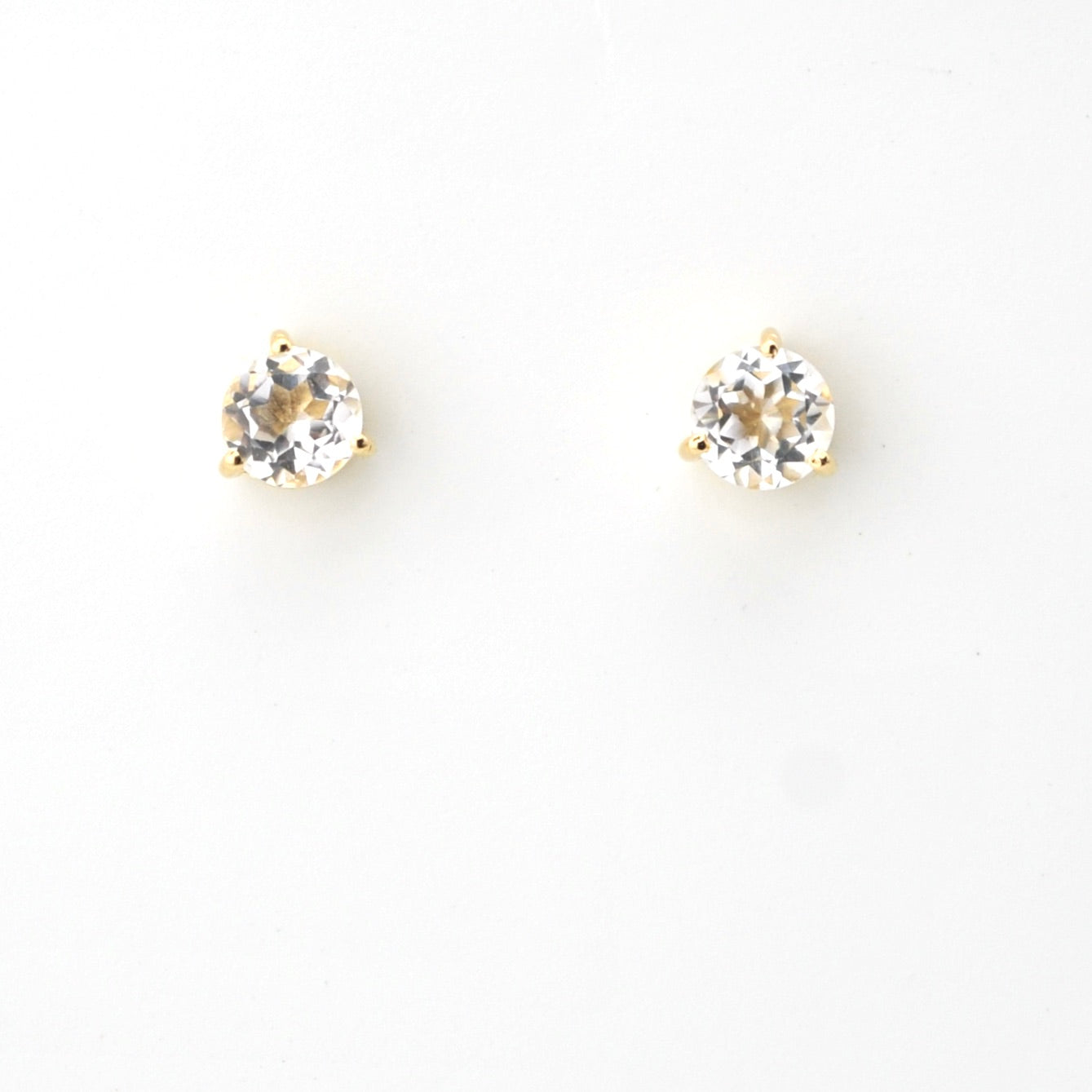 Pair of gold stud earrings with clear gemstones on a white background