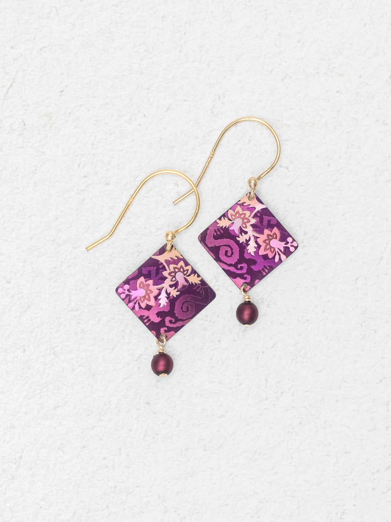 Pair of square-shaped earrings with floral pattern and purple beads on a white background