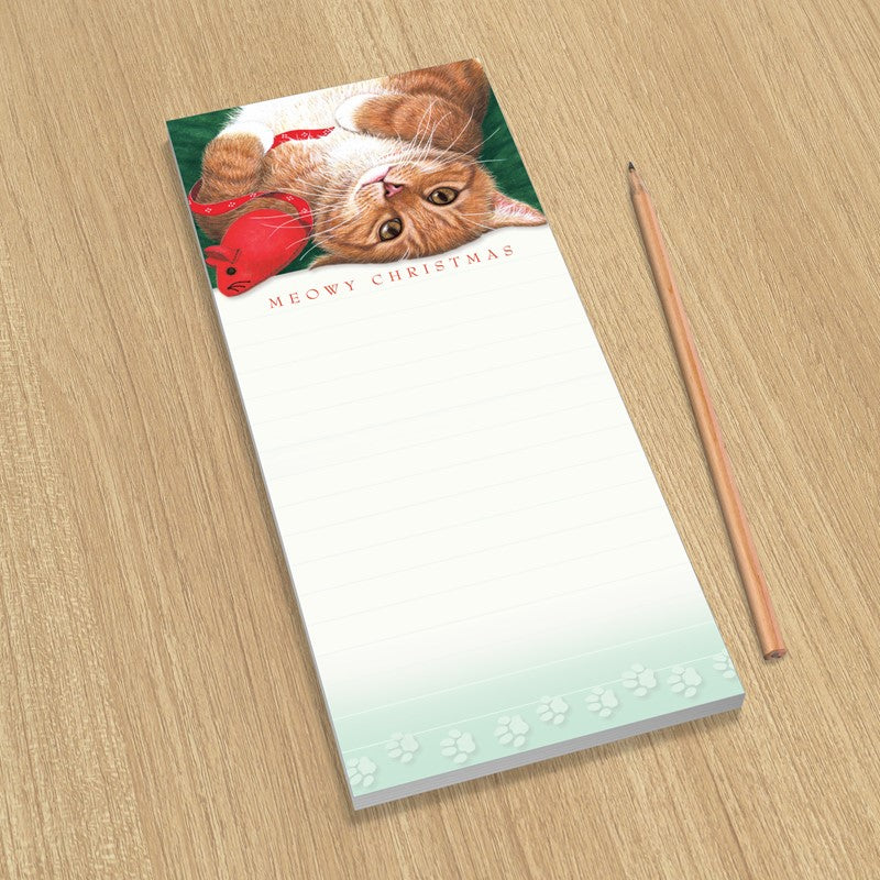 Notepad with a cat illustration and 'Meowy Christmas' text on a wooden surface with a pencil.