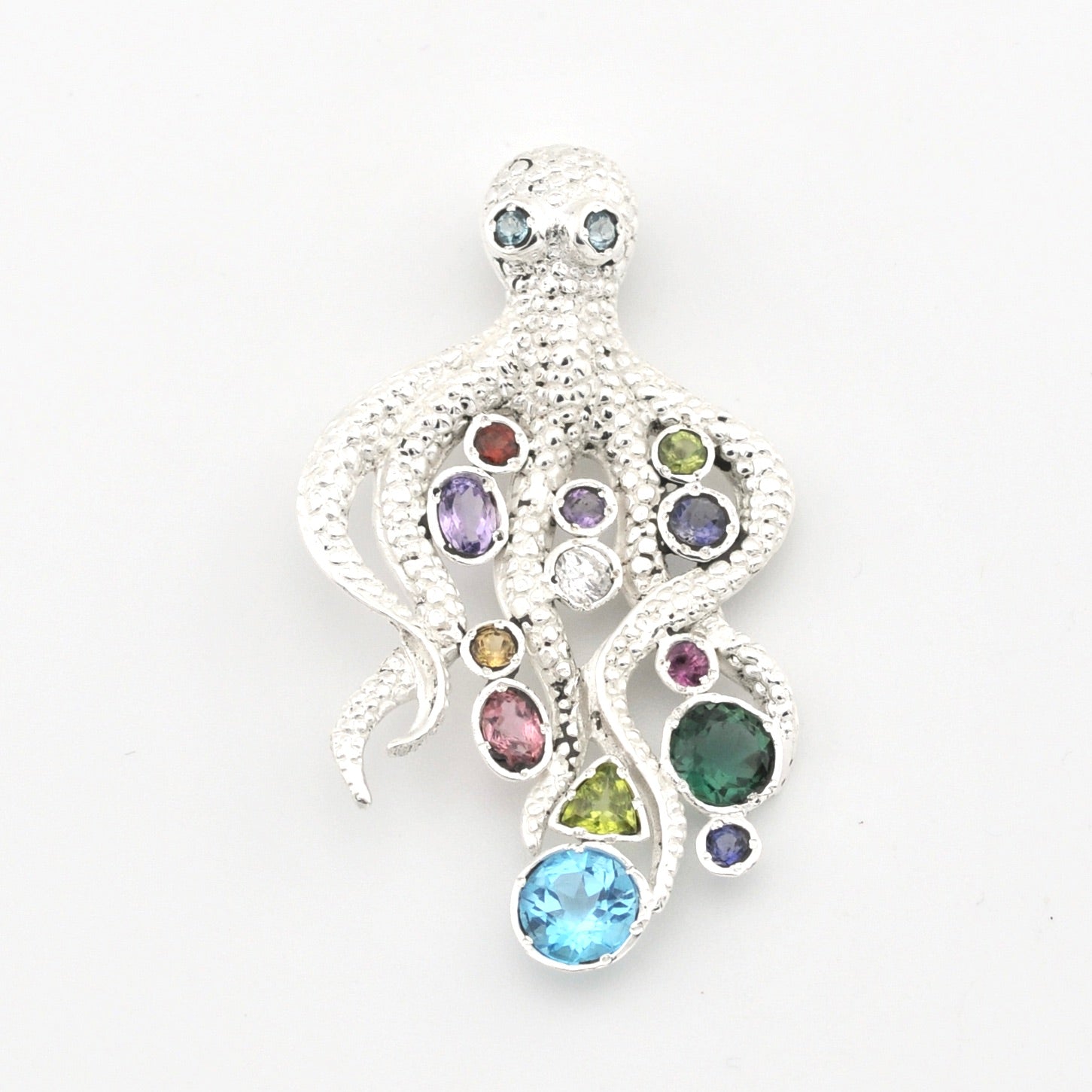 A silver octopus-shaped pendant featuring multiple colorful gemstones in various shapes and sizes, set against a plain white background.