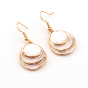 Pair of gold and white layered earrings on a white background