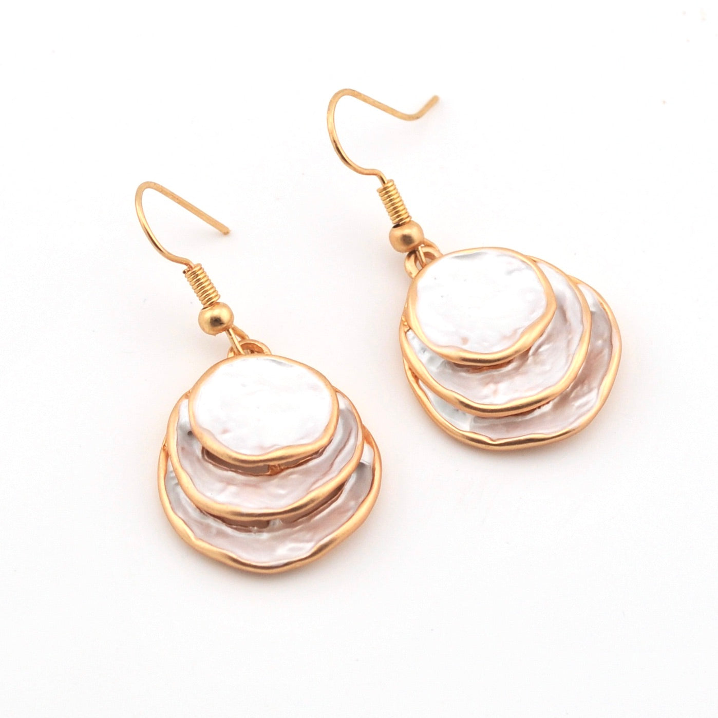 Pair of gold and white layered earrings on a white background