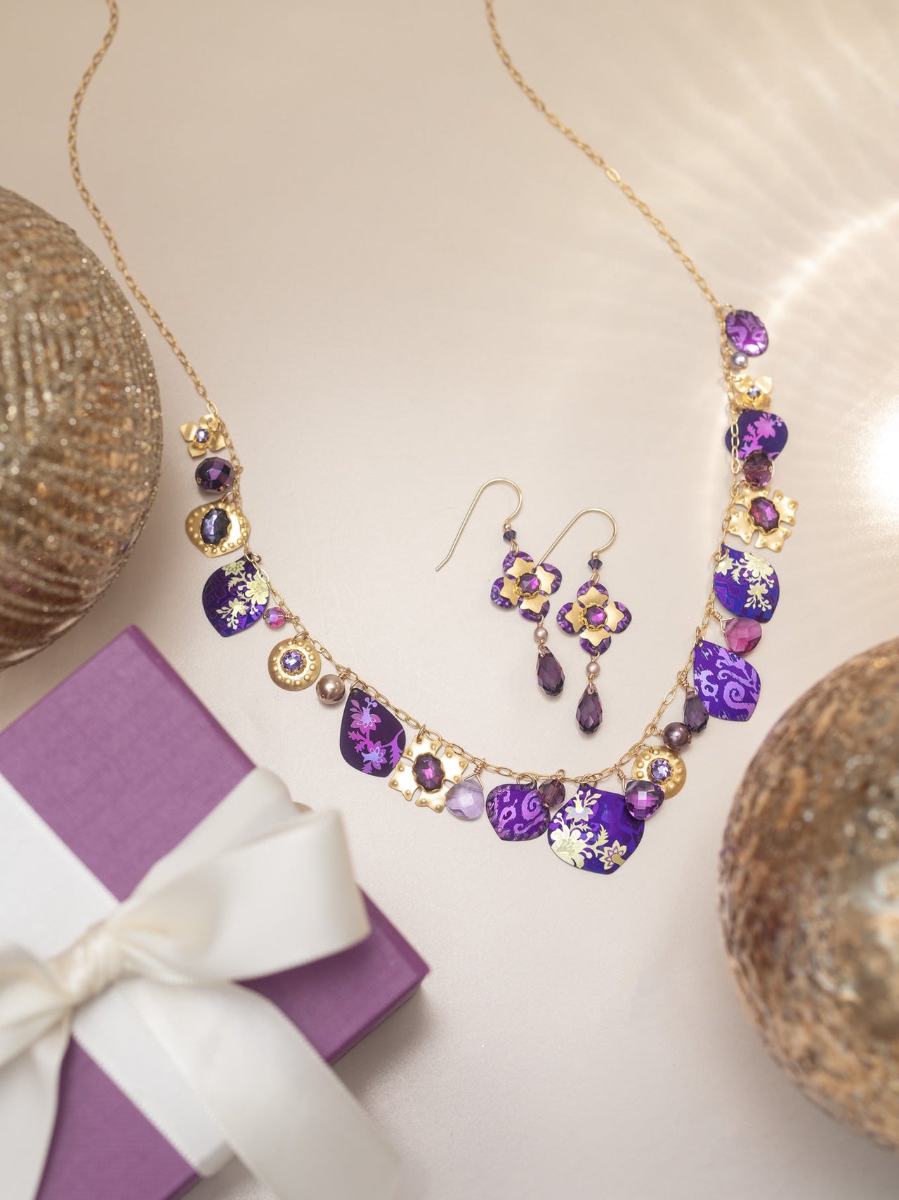 Purple jewelry set with necklace and earrings on a light background