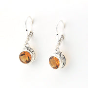 Pair of silver earrings with amber stones on a white background